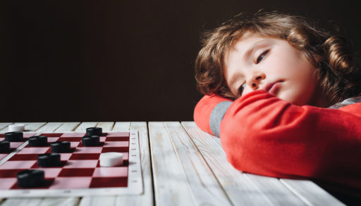 A bored child in front of a checker game