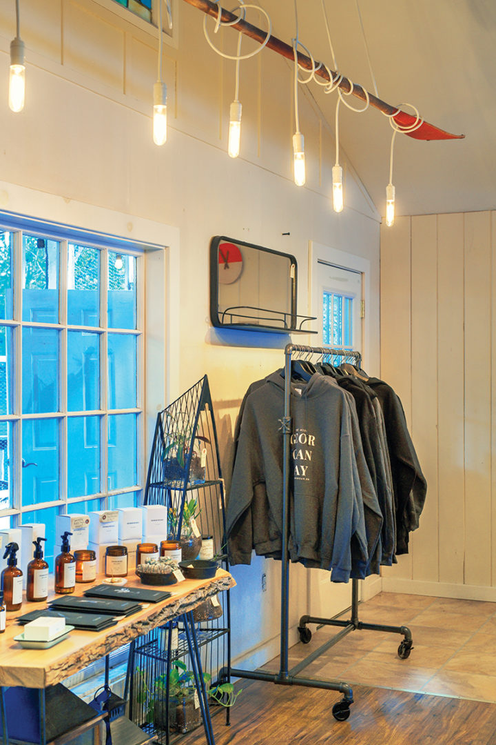 Sweaters and clothing on a rack, merchandise on a table inside The Hive store