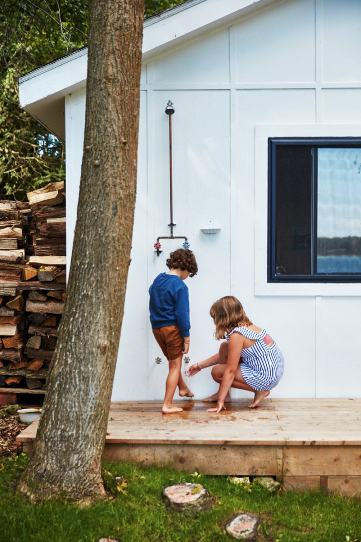 kids playing at an outdoor shower outside Heather Rice's cabin