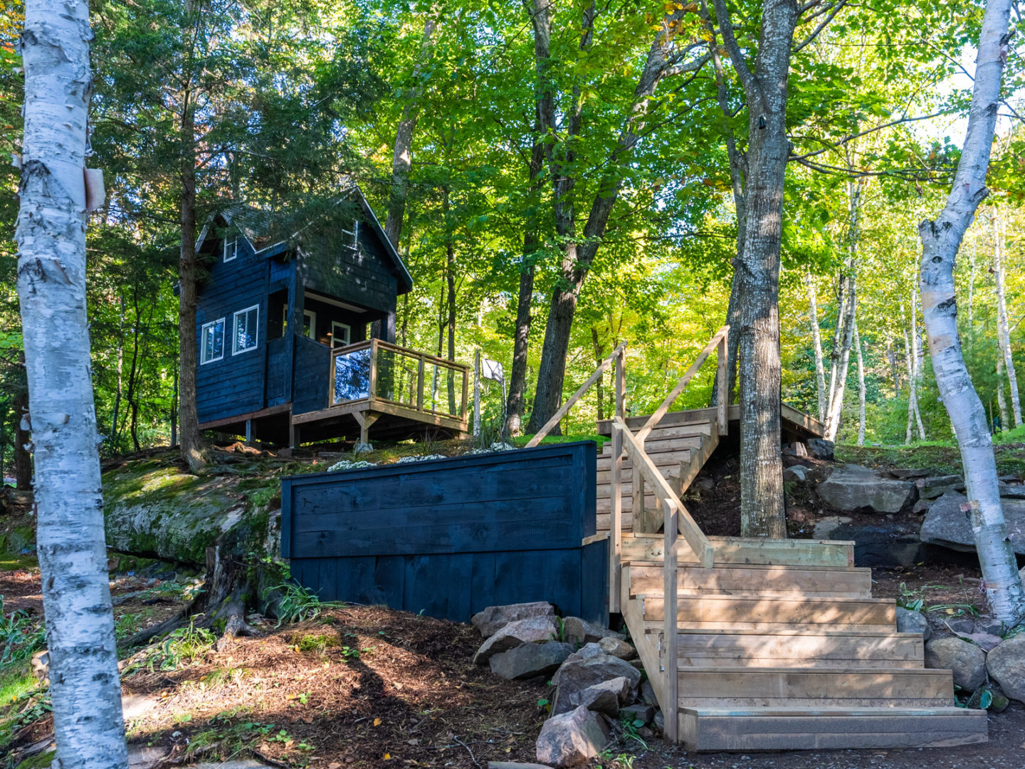 A small bunkie on a hill, with stairs leading up to the building.