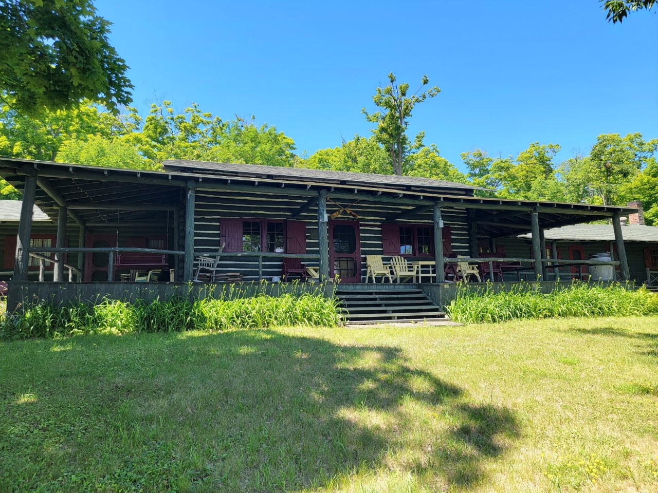 Big front porch of a large front cabin, with yellow adirondack chairs on the porch.