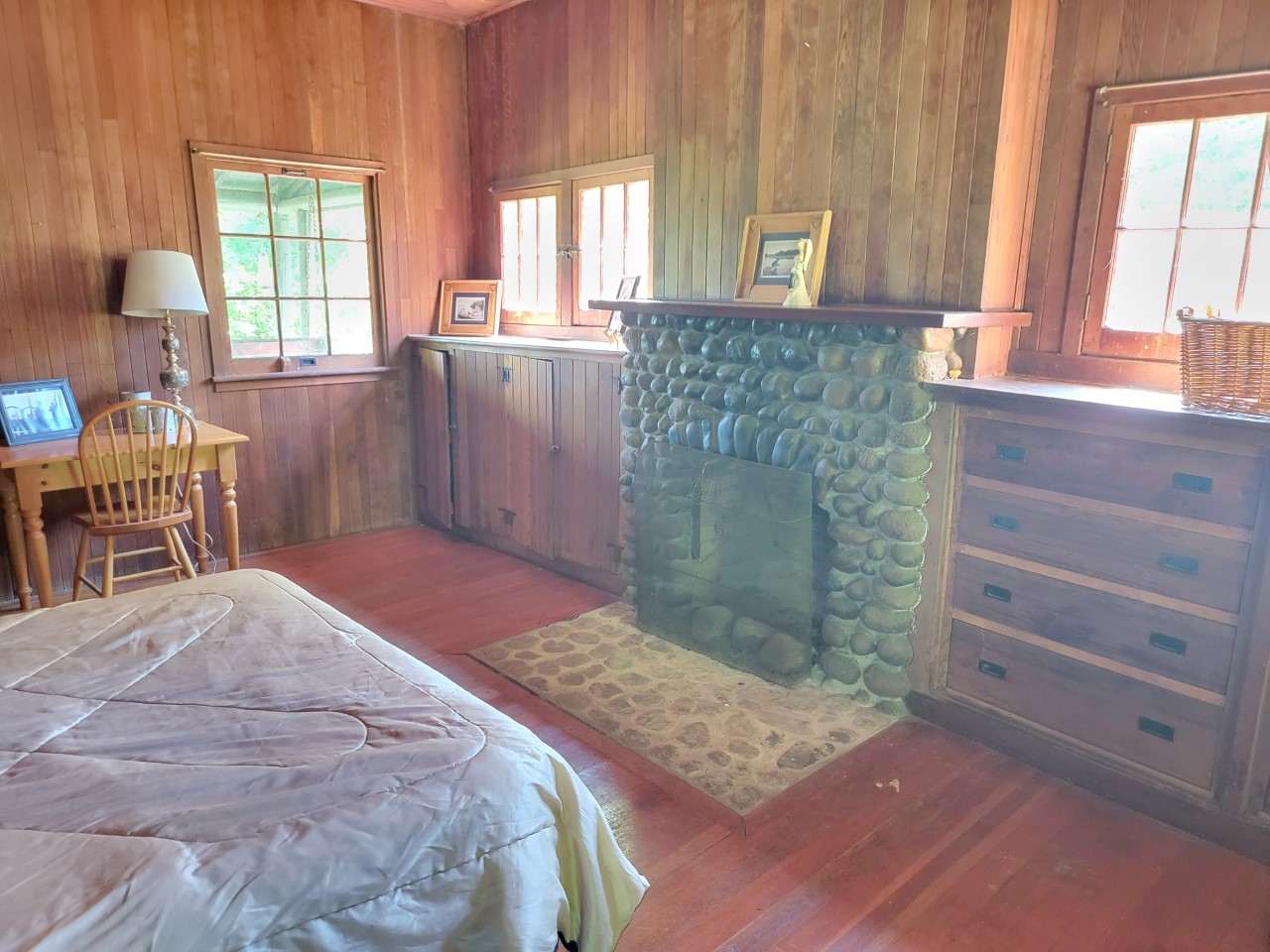 Interior of a wood-panelled room with a double bed and a stone fireplace.