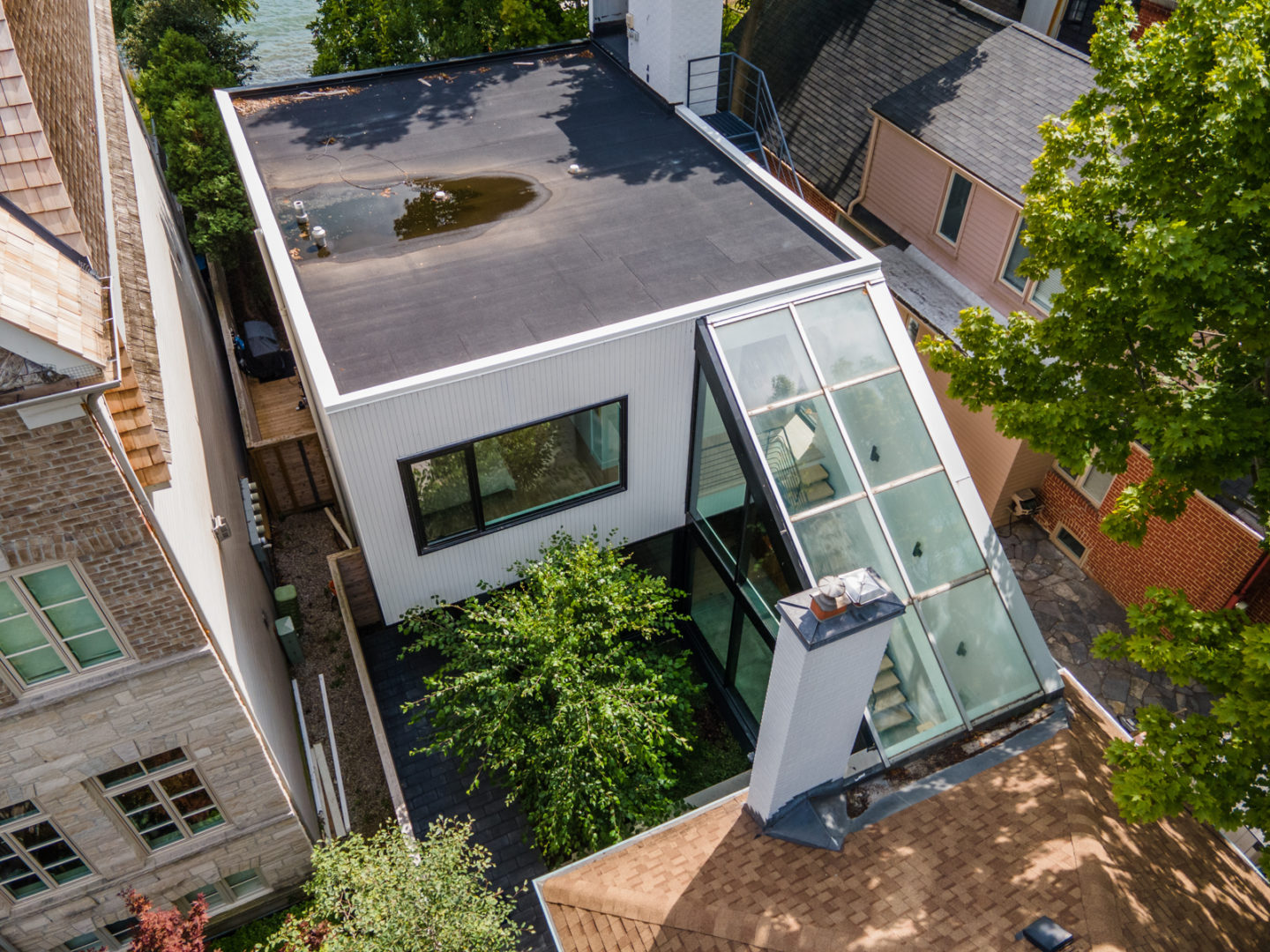 Overhead view of a home with two units, connected by a hallway with a glass ceiling that reveals a staircase inside.