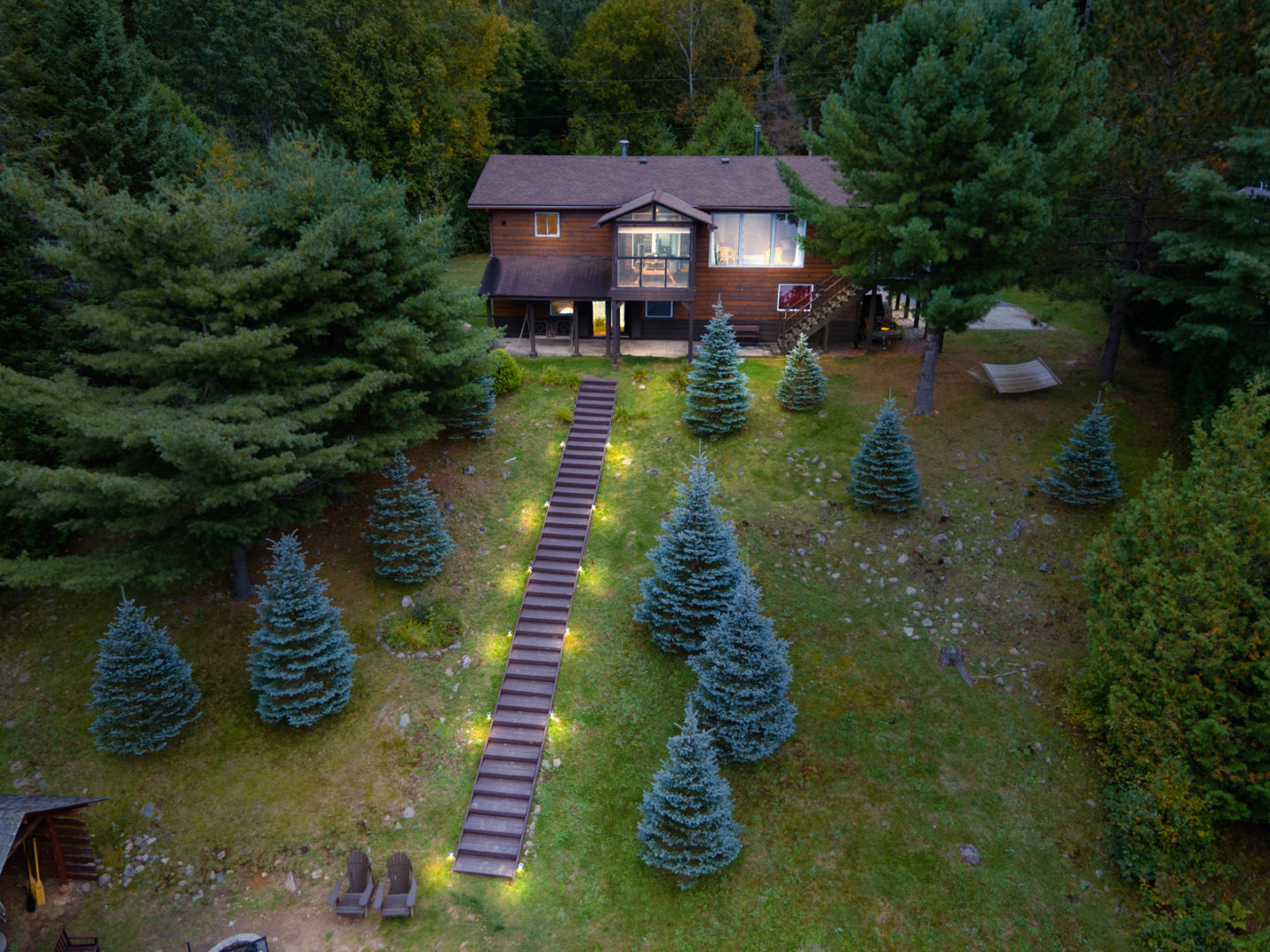 A large house on top of a hill, with stairs leading down the slope that are illuminated with lights all the way down.