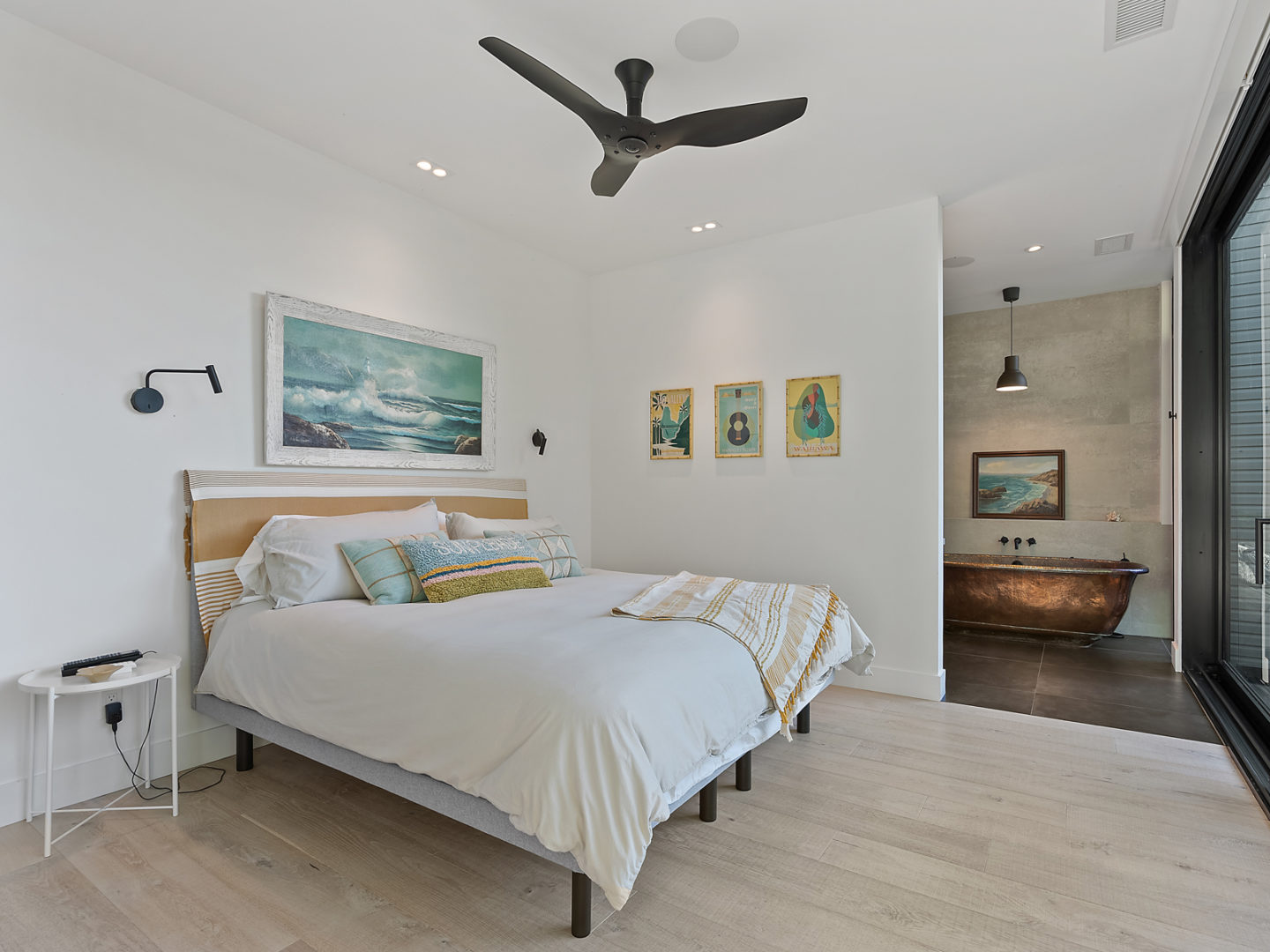 A large, bright bedroom with a simple bed and bathroom off to the side.