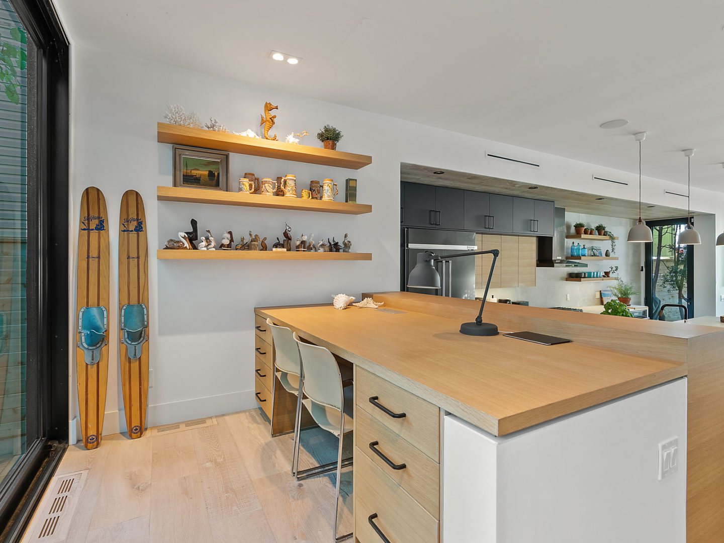 A big desk with drawers and a chair, looking out over a kitchen space.