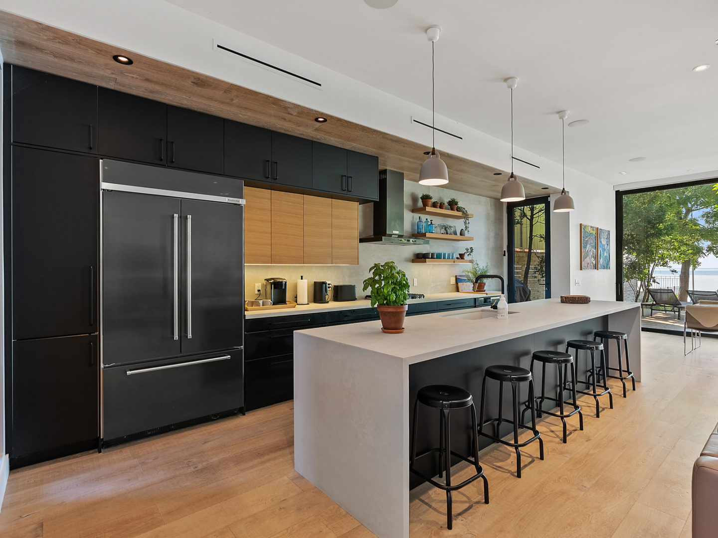 A big modern kitchen that has an island with barstools and stainless steel appliances.