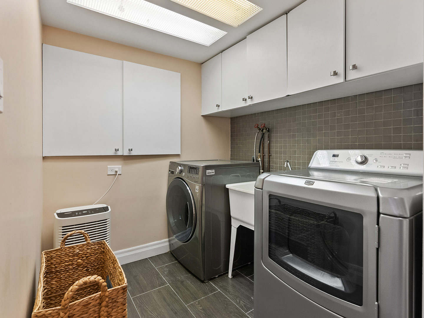 A laundry room area with a washing machine, a dryer, and lots of overhead cupboard space.