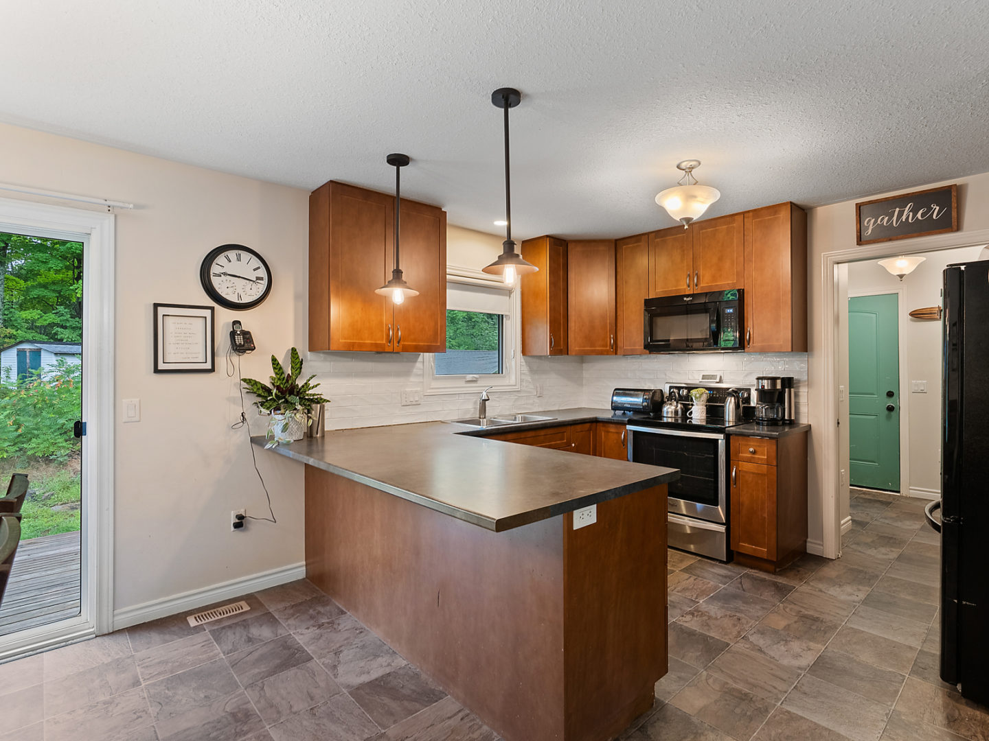 A modern kitchen ares with warm wooden cabinets and large countertops.