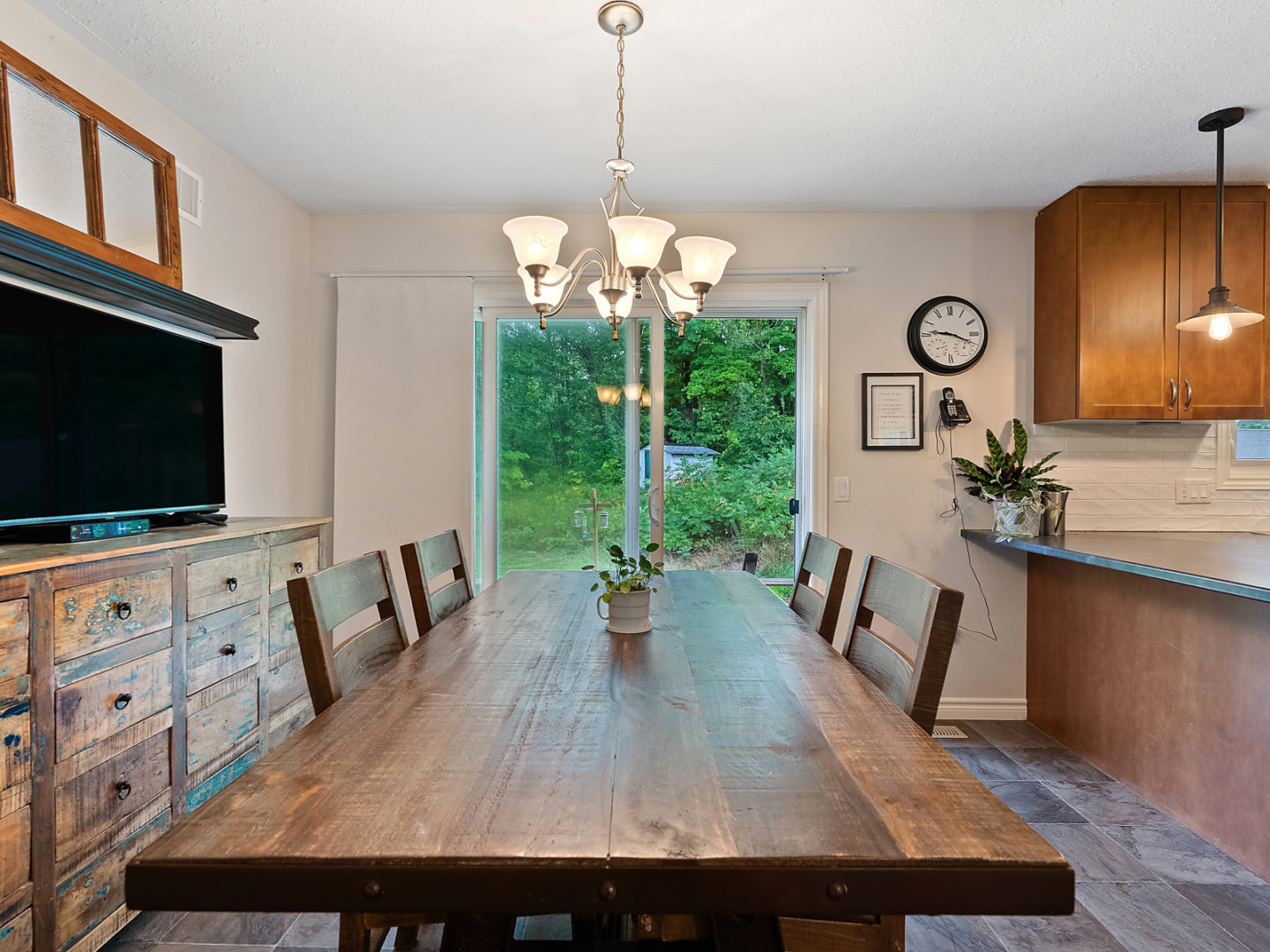 A dining room table in front of a glass door leading into a backyard area.