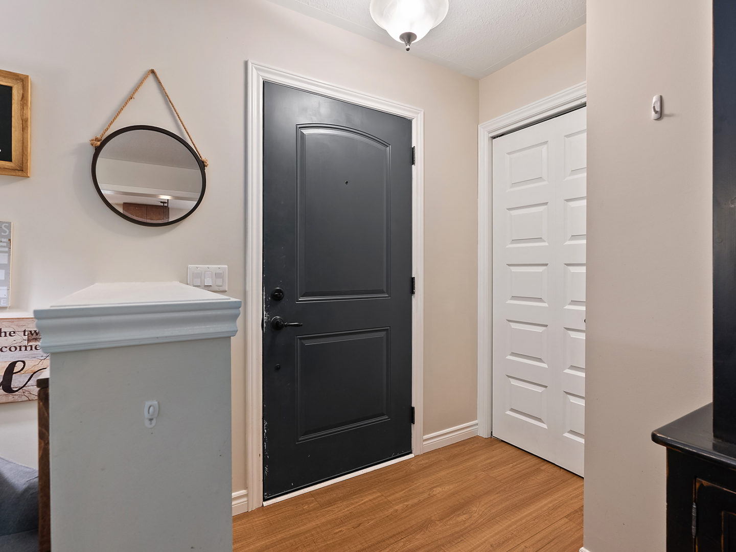 A small front entrance area with a mirror hanging on the wall beside a painted black door.