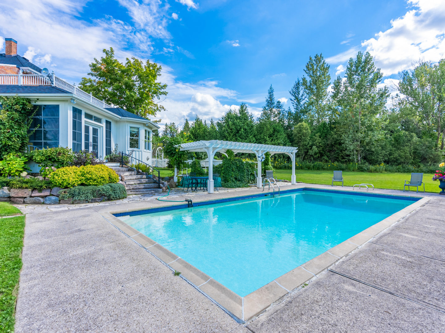 A large rectangular swimming pool full of turquoise water, surrounded by patio.