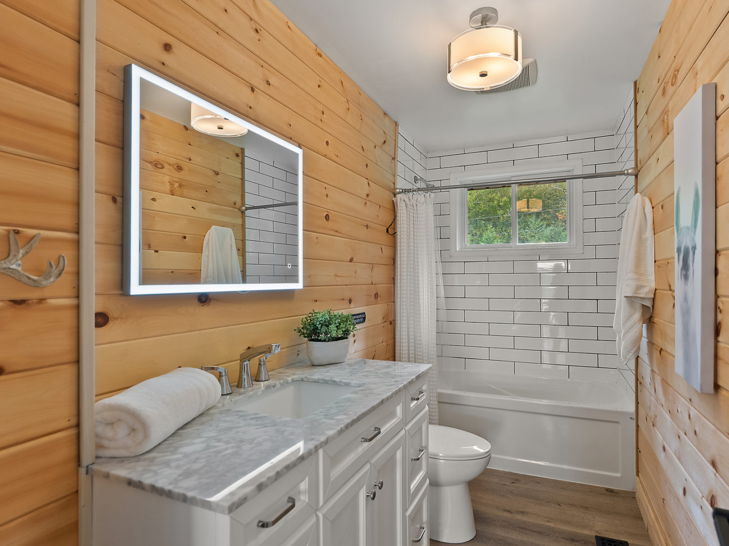 A modern bathroom with a large sink, a bathtub with a shower, and a toilet.