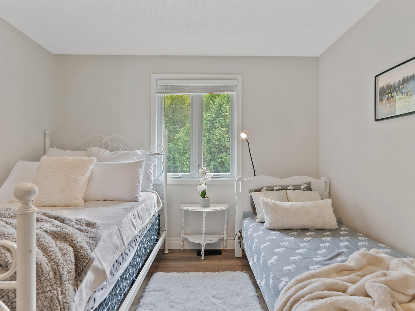 A small, bright bedroom with two single beds on either side of a window.