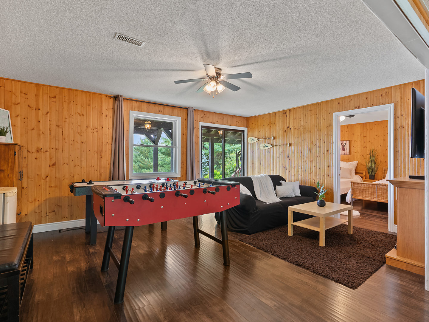 A spacious living space with a foosball table in the middle of the room and a couch beside it.