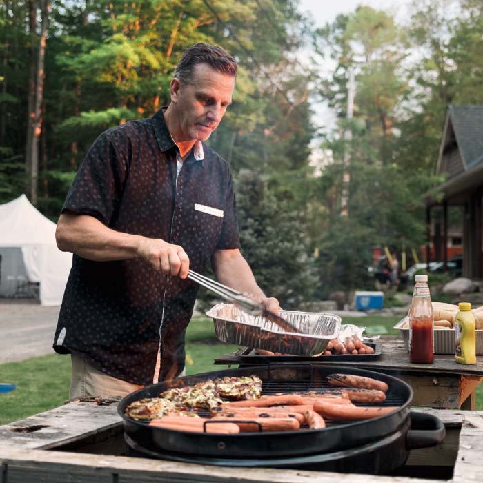 A man grilling hot dogs on the barbecue