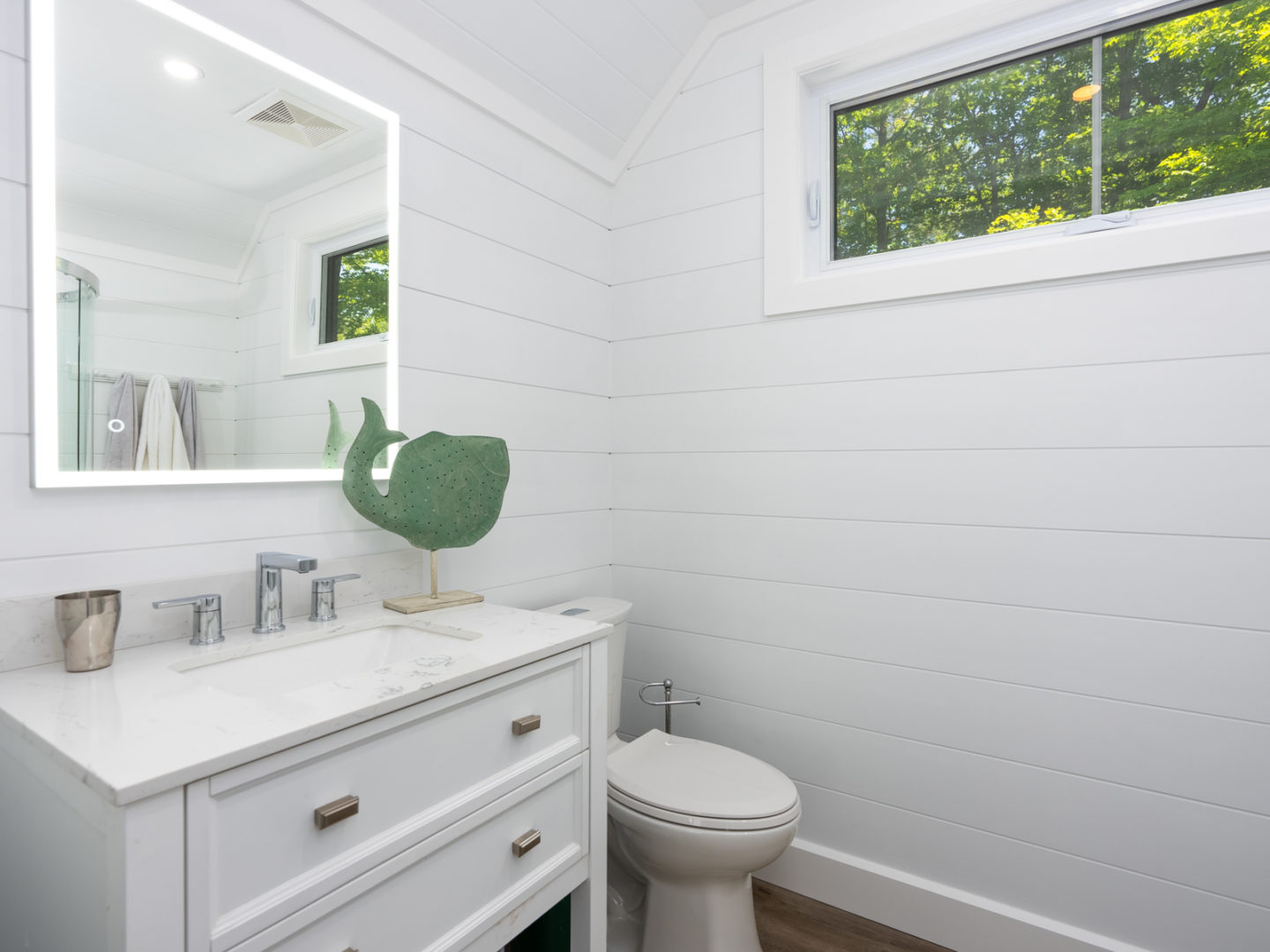A small bathroom with white walls and cupboards.