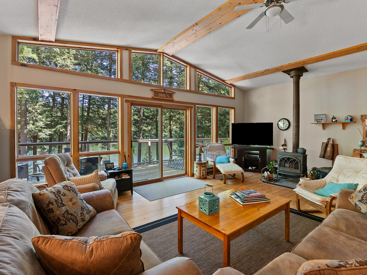 A bright living room with couches, a fireplace, and floor-to-ceiling windows across one wall.