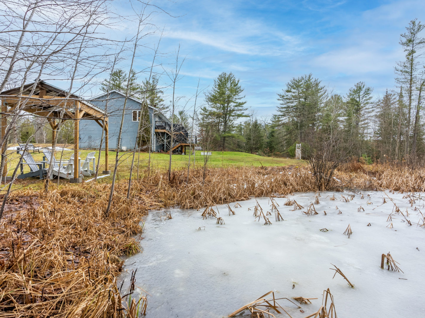 A frozen pond with a small house in the background.
