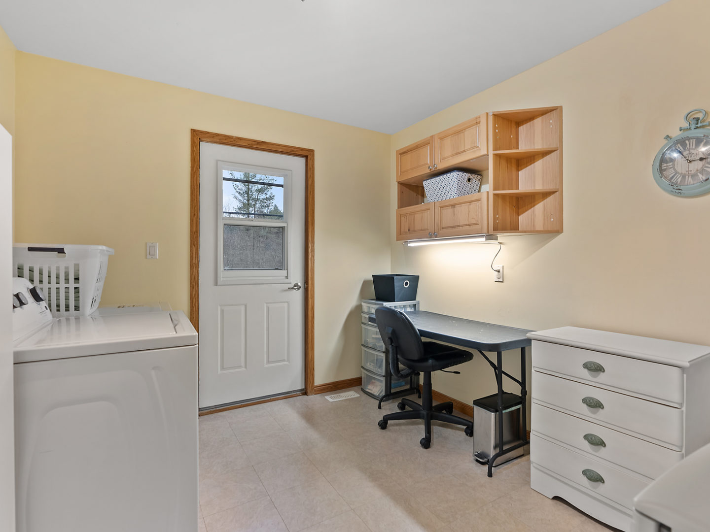 A small room with a desk and a laundry area.