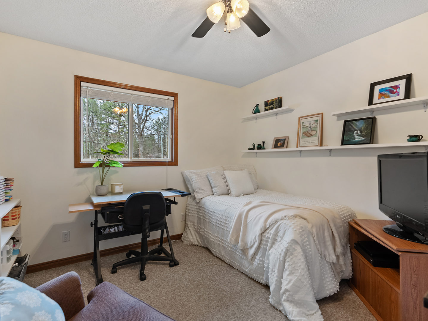 A small bedroom with a single bed, a window, and a desk.