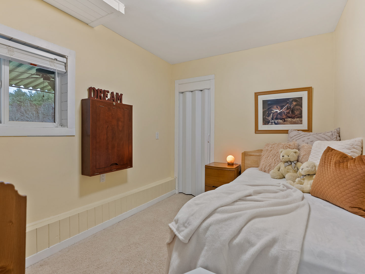 A small bedroom with a bed, a window, and a bedside table.