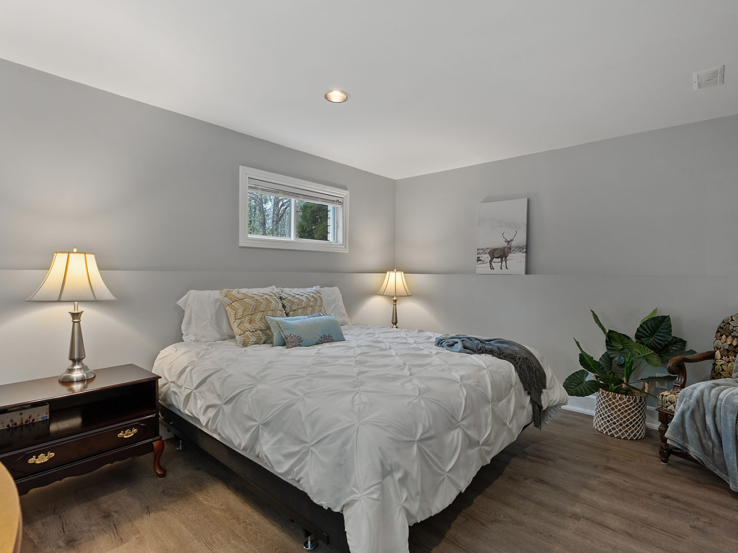 A bedroom with a big bed, a bedside table, and a small window.