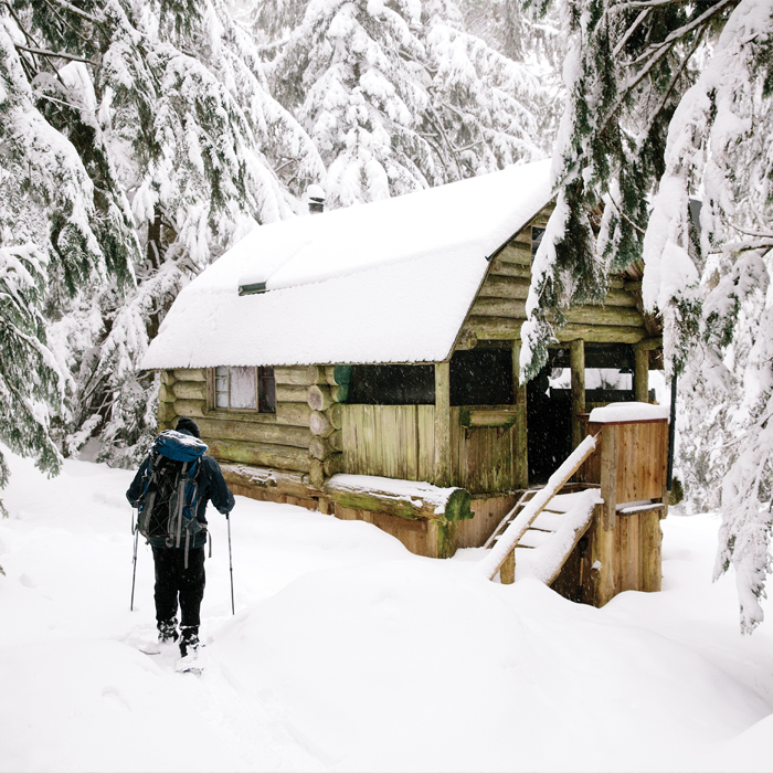 A man skiing towards a snow-covered cabin