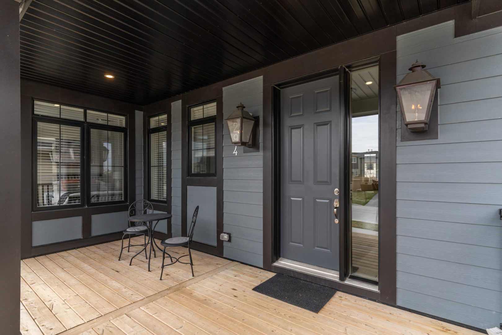 A large front porch with a small table and two chairs sitting to the side of the front door.