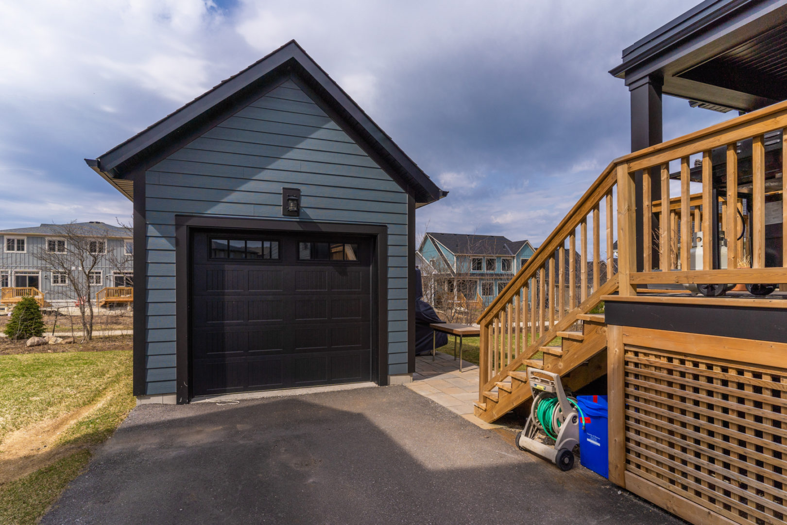 A detached single car garage with a dark blue exterior and a black garage door.