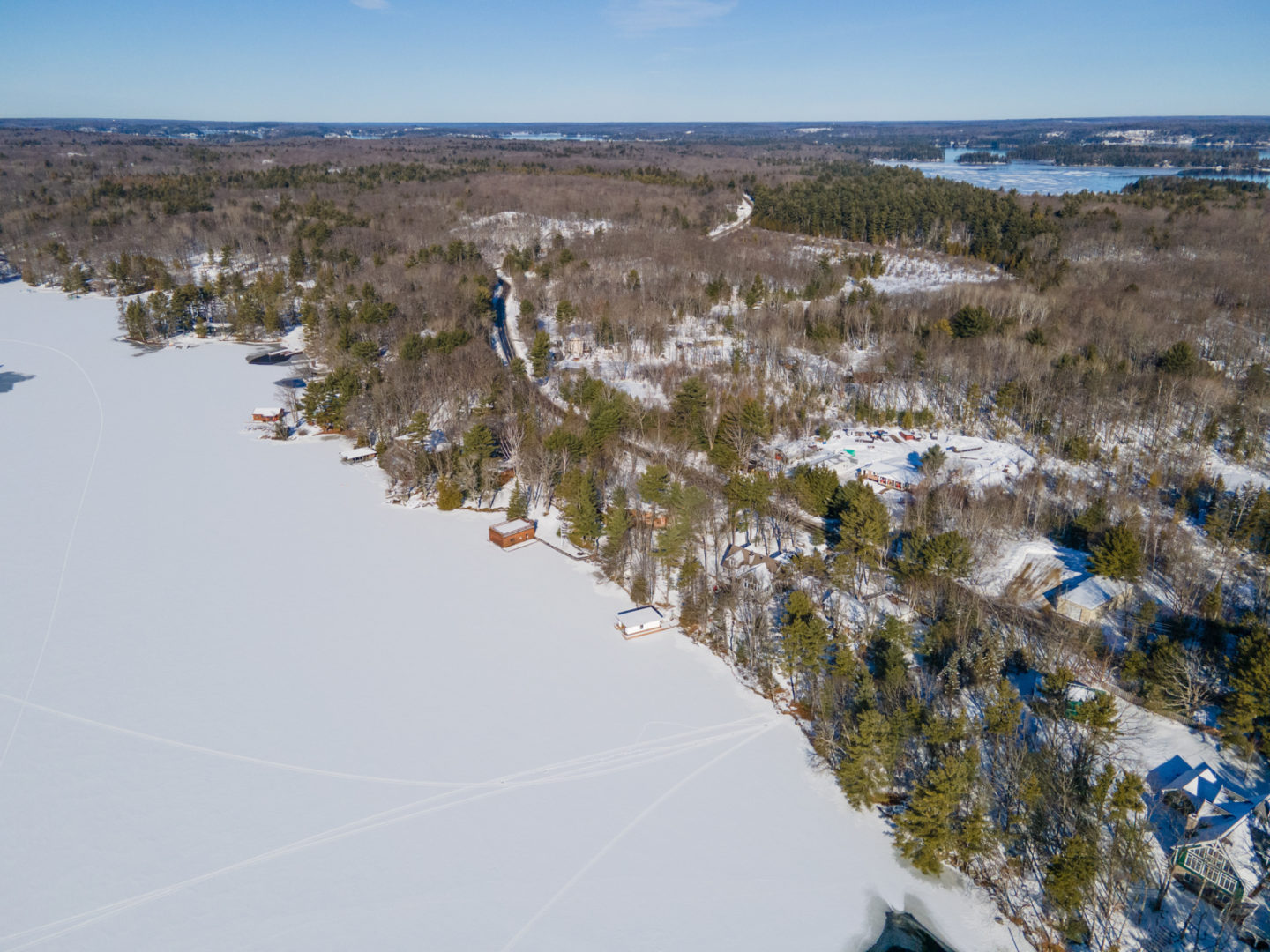 A frozen stretch of lake in the winter, covered in snow.