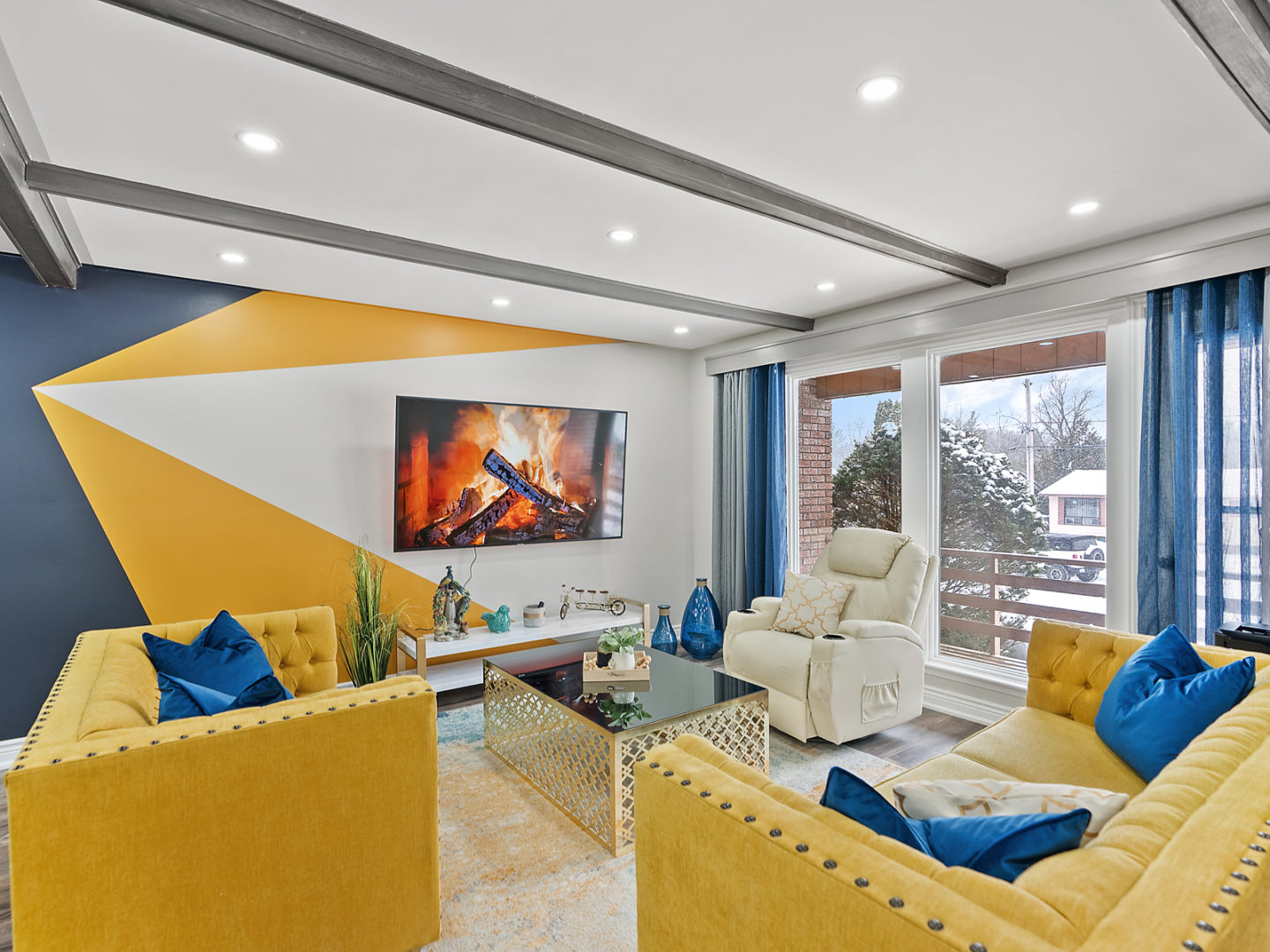 A bright living area with bold yellow seating and an accent wall painted navy, yellow, and blue.