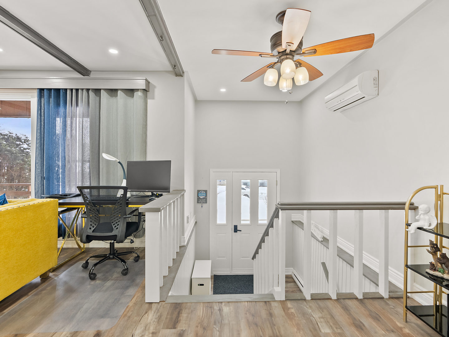 A small staircase leads down from a living space to a landing with a front door entrance.