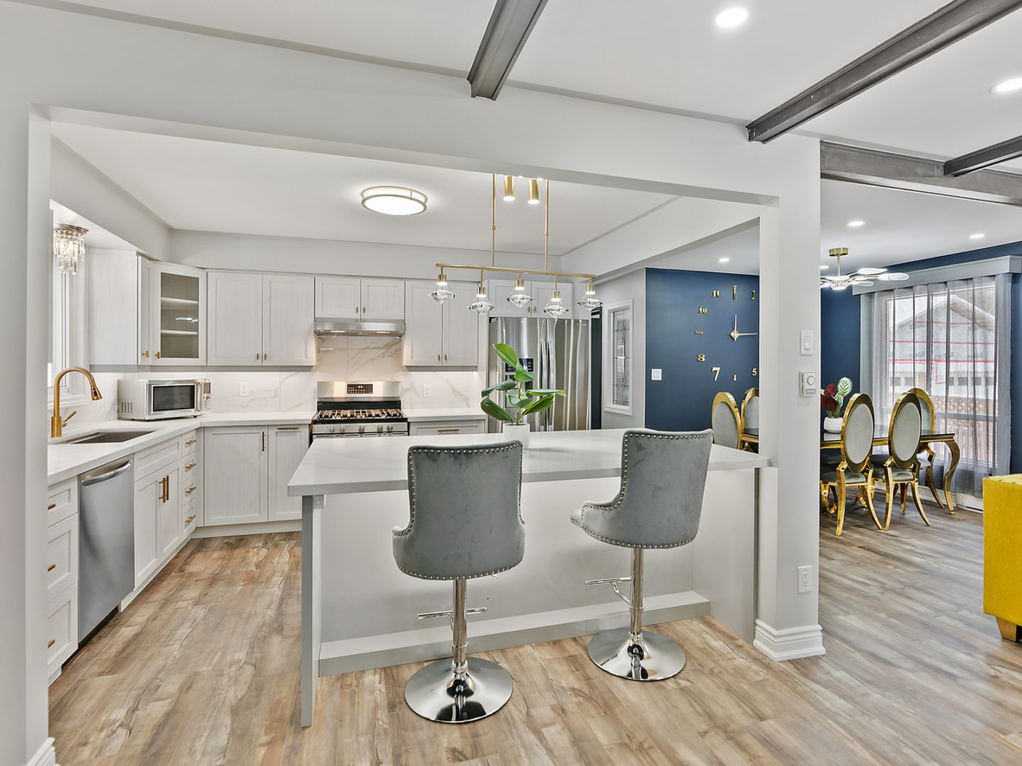 A spacious kitchen with white cupboards, updated appliances, and a large island with two barstool seats.