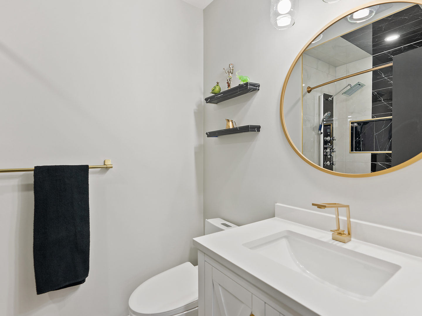 A small bathroom with a toilet, a sink, and a gold-rimmed mirror.
