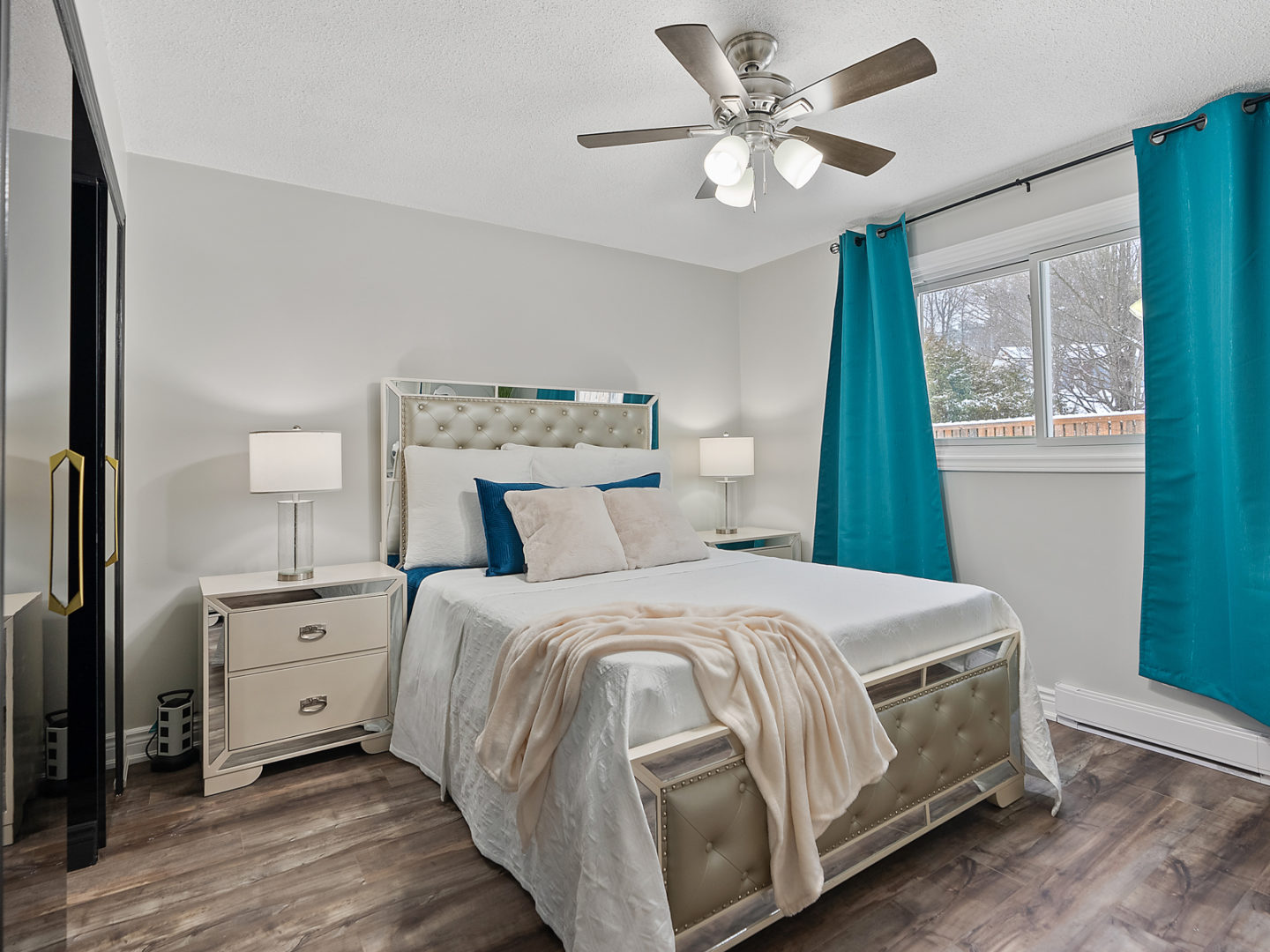 A roomy bedroom area with a large bed, a ceiling fan, and a window.