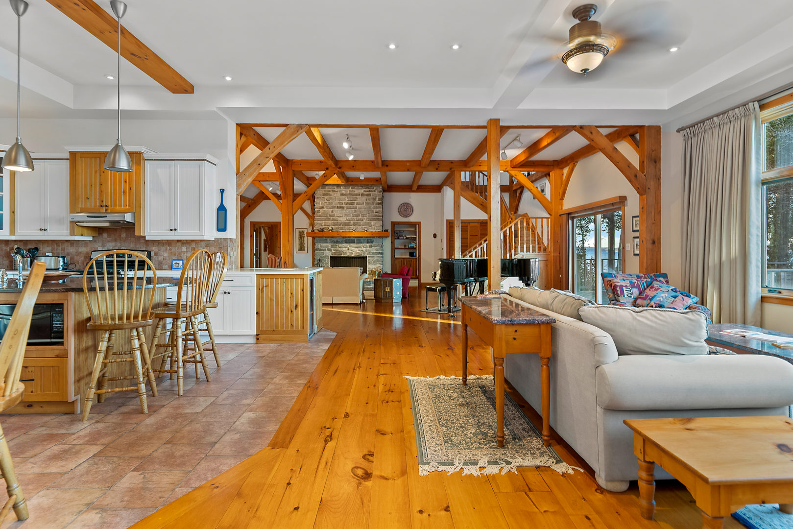 An open-concept space with a couch sitting area off to one side and a small kitchen off to the other. A grand piano can be seen on the other side of the room.