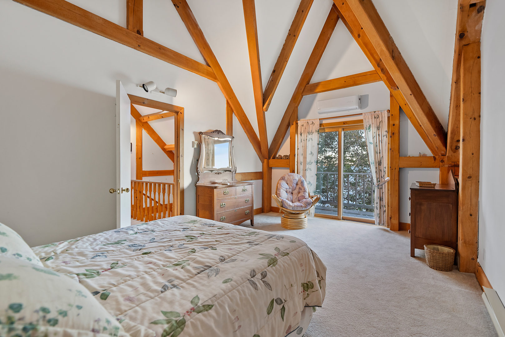 A small, bright bedroom with white walls and wooden beam accents.