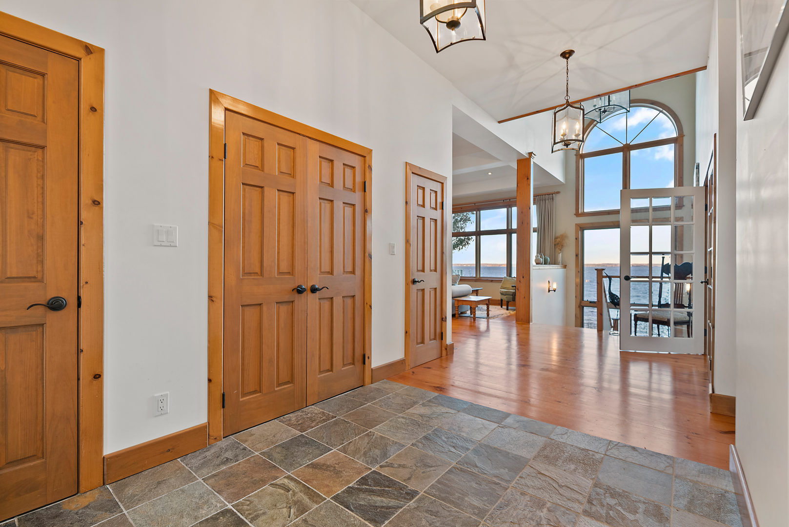 A spacious second-floor hallway area with double doors throughout and a mix of tile and hardwood flooring.