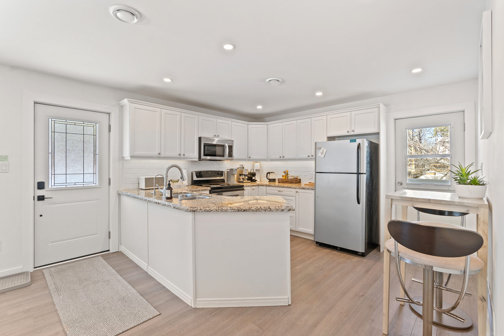 Inside the entrance of a cottage bungalow. A bright, open-concept, modern design, with a small but updated kitchen right off the entrance.