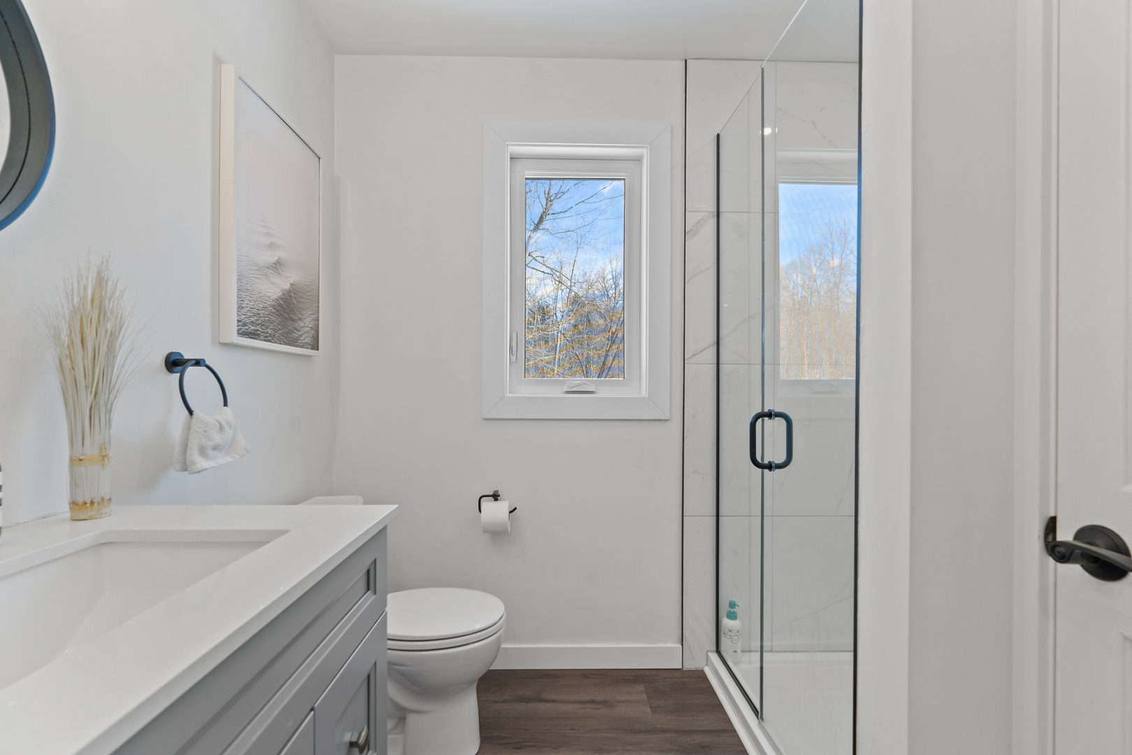 A small but modern bathroom with a toilet, a sink, and a walk-in shower.