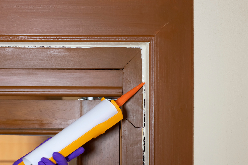 Close-up of someone applying caulk around a door frame