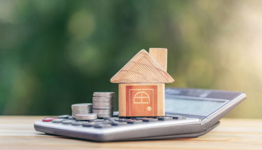 House is placed on the calculator and coin is on the calculator. mortgage stress test