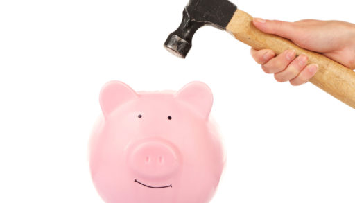 Female hand holding hammer above pink piggy bank isolated on white, closing costs