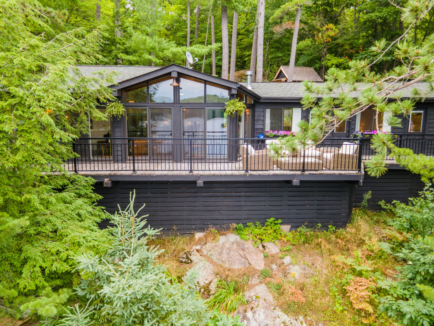 Exterior of a luxury cottage with a wrap-around deck and floor-to-ceiling windows.