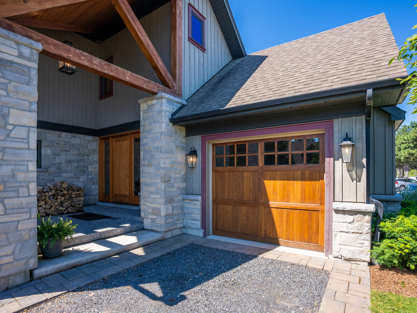 The front of a large stone house, with a matching wood panelled front door and garage door.