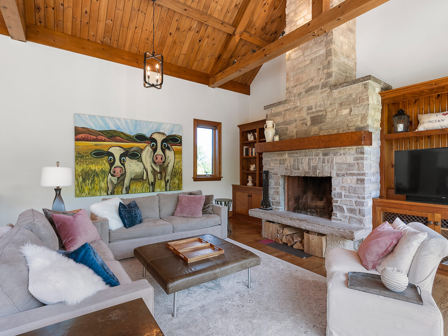 A living area with an L-shaped couch, a cozy rug and a stone wood-burning fireplace.