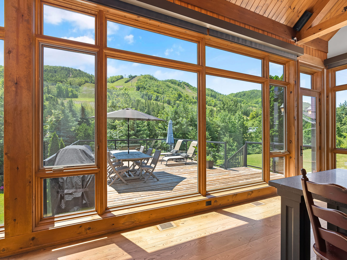 Floor-to-ceiling windows stretching across the length of a house. A door opens up to a large deck off the kitchen.