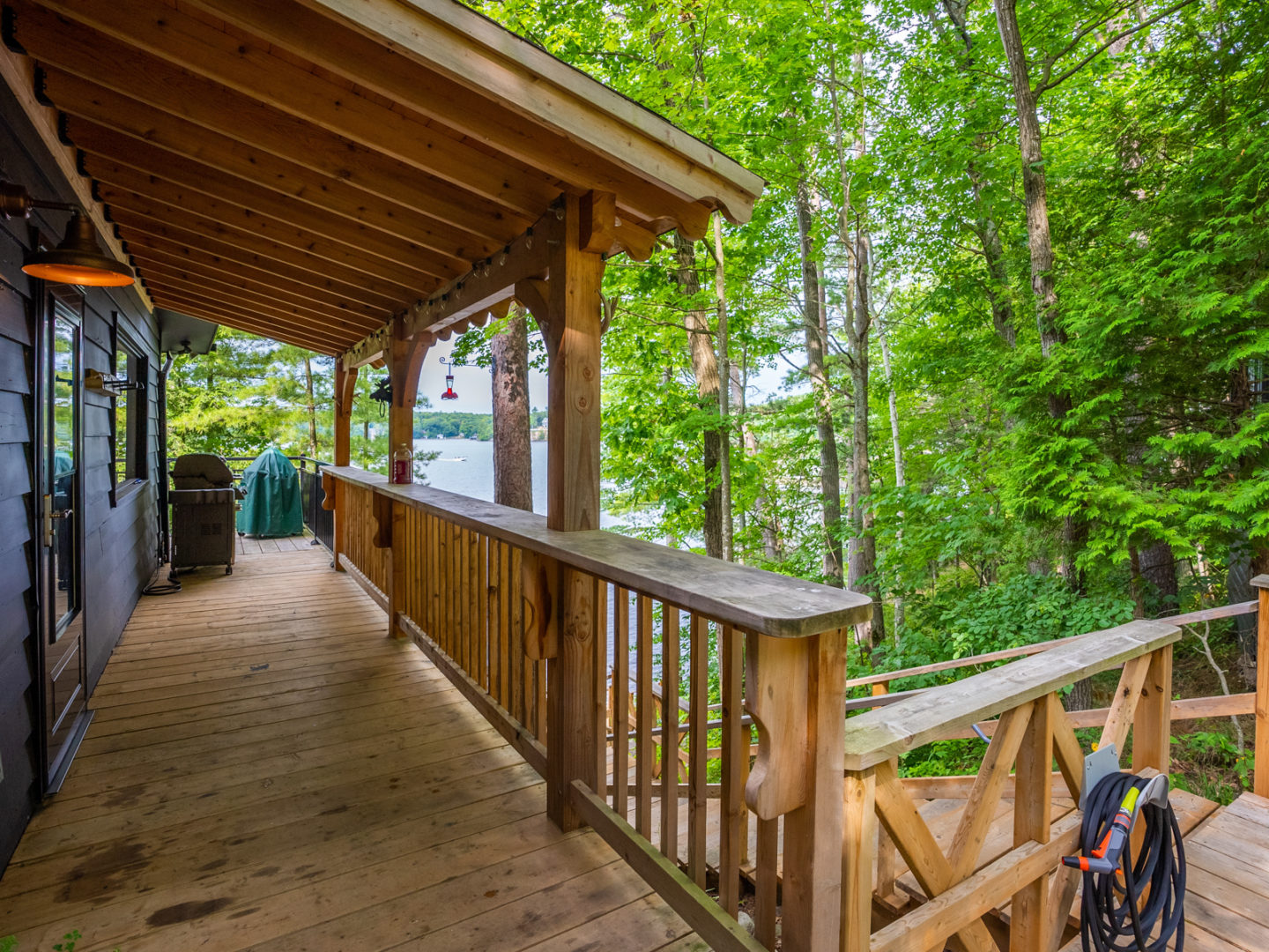 A spacious deck around a cottage, with the top of a staircase leading down to the lake level.