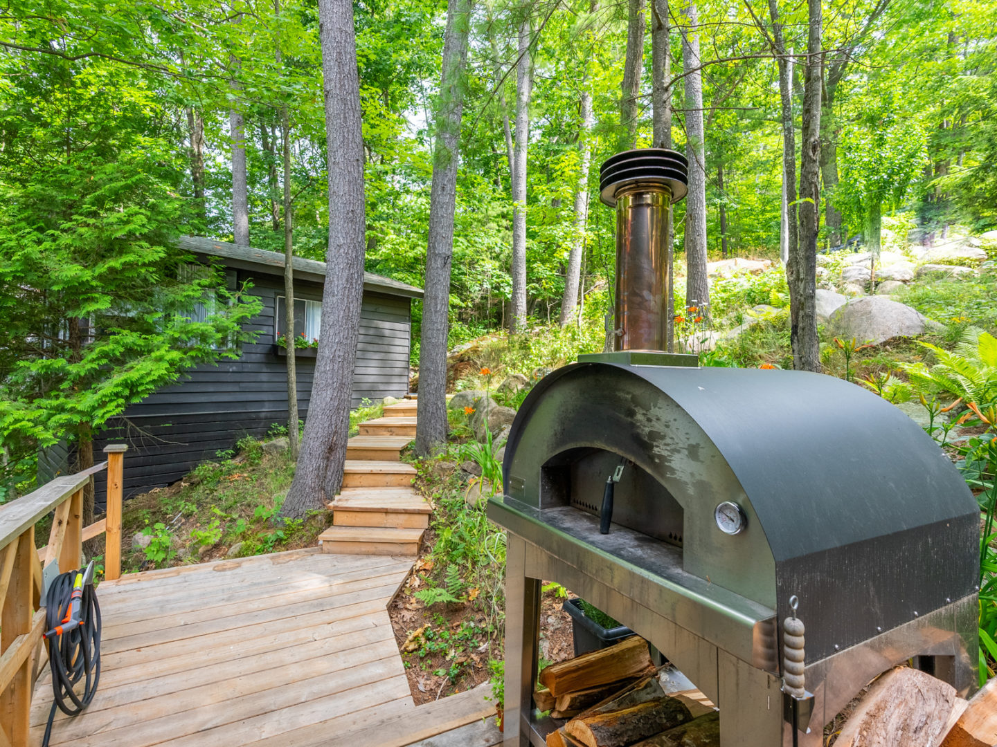 An outdoor stone oven sitting on the deck of a large cottage.
